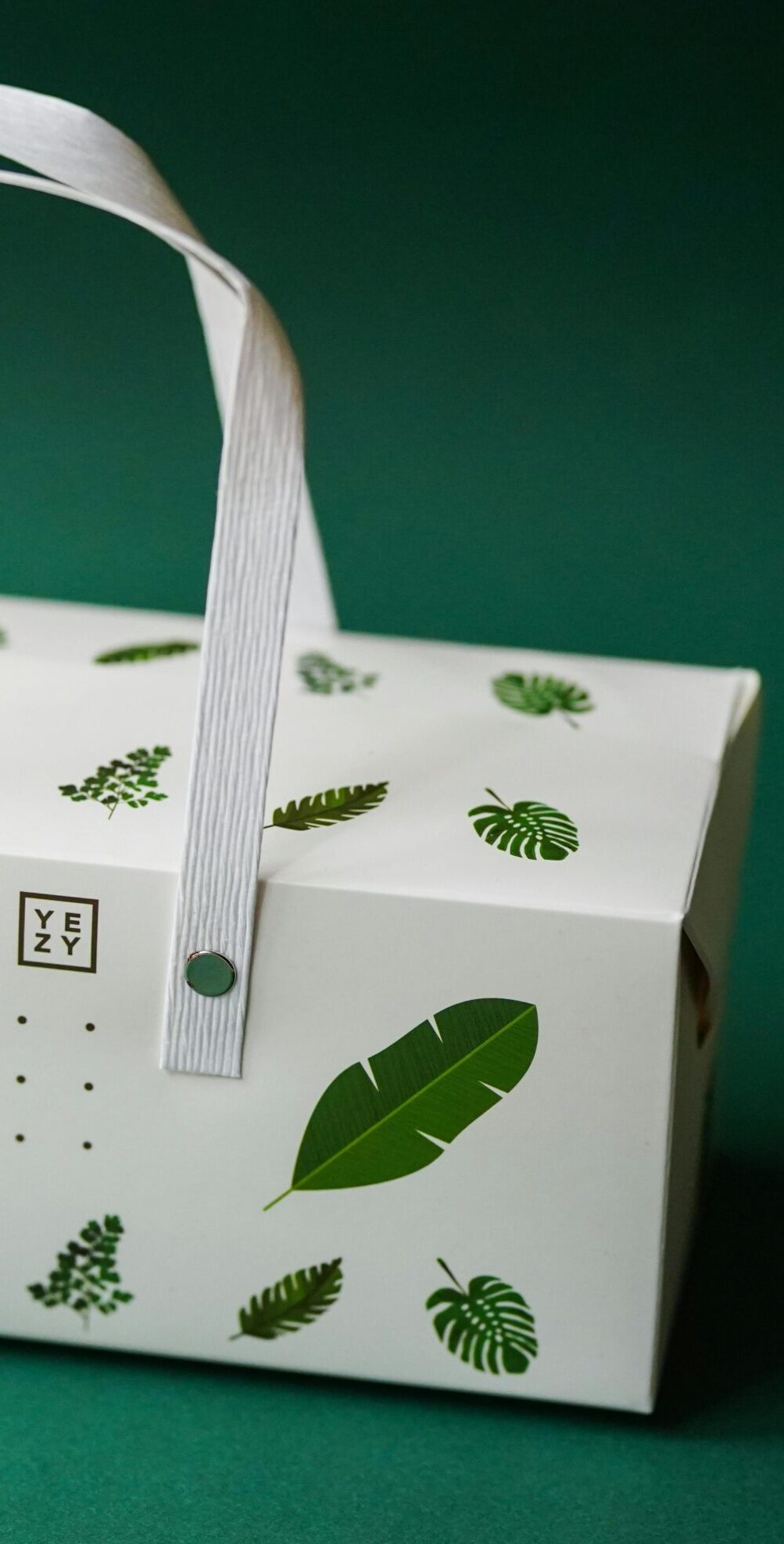Elegant packaging box featuring watercolor leaf design on a green background.