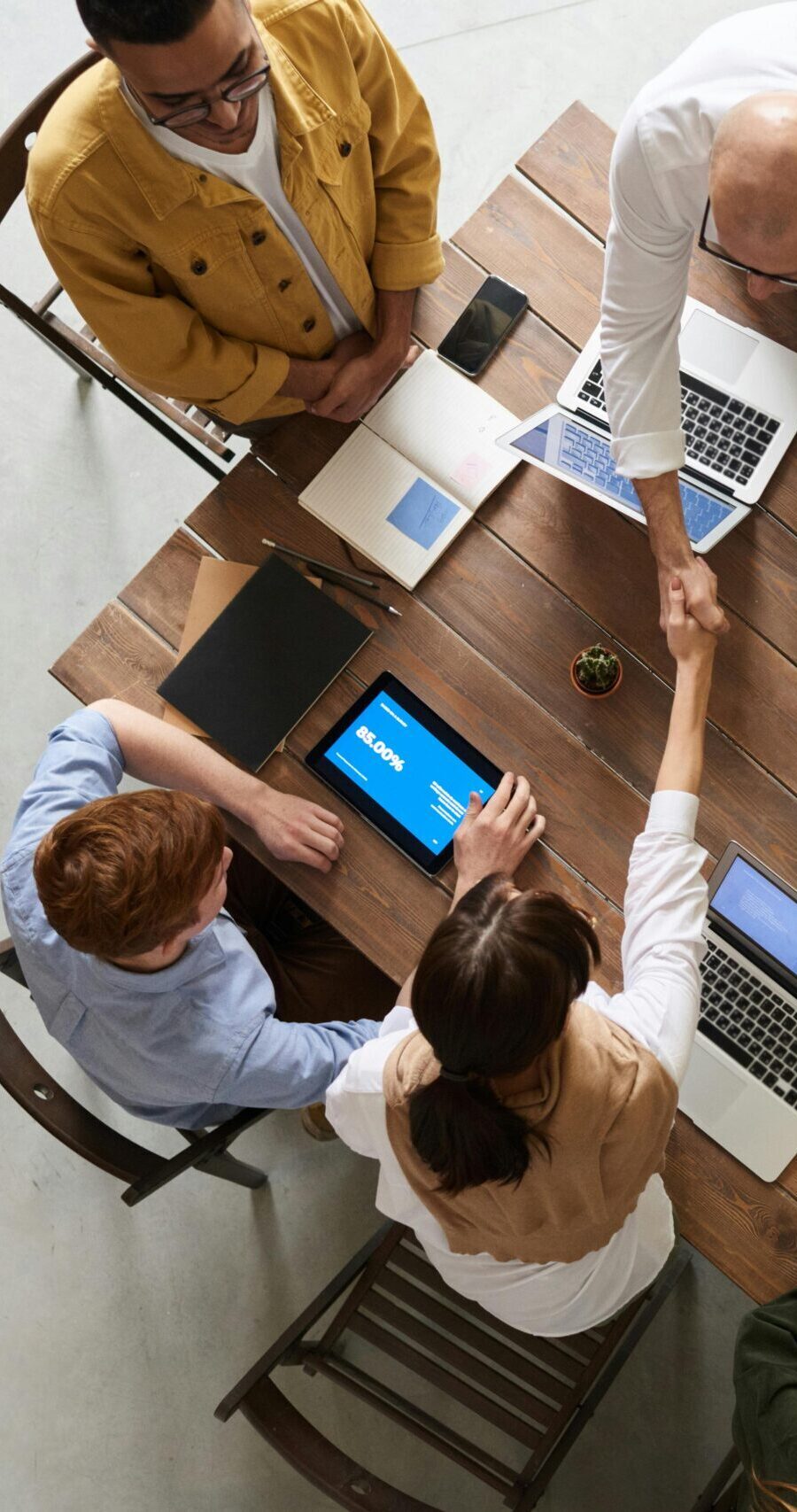 Top view of a diverse team collaborating in an office setting with laptops and tablets, promoting cooperation.