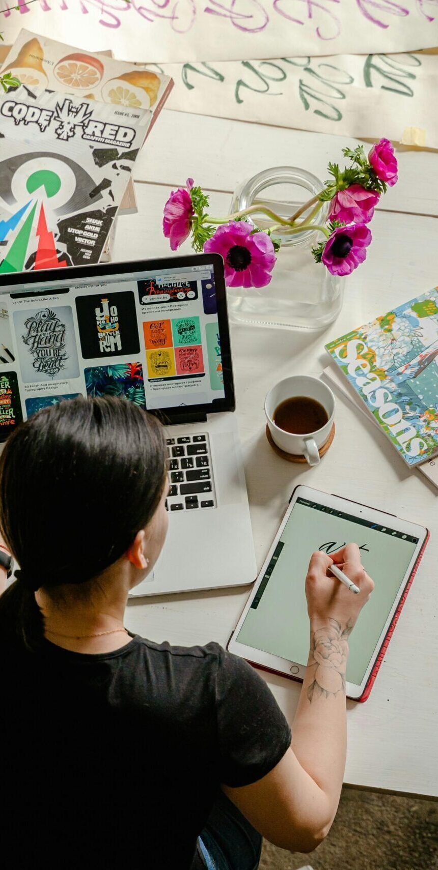 Artistic workspace featuring calligraphy and digital design on a tablet and laptop.