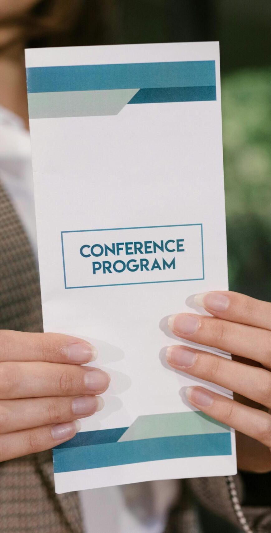 A professional holding a conference program brochure, ready for event attendees.
